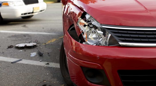 Smashed front end of a red compact car